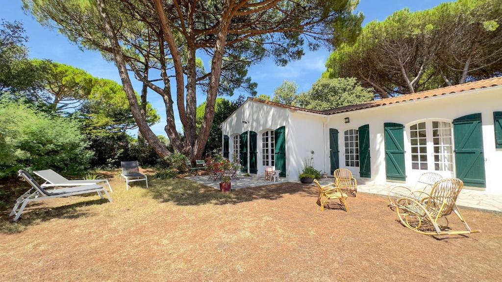 een wit huis met stoelen en een boom bij Charmante villa de plain pied à proximité de la plage in La Couarde-sur-Mer