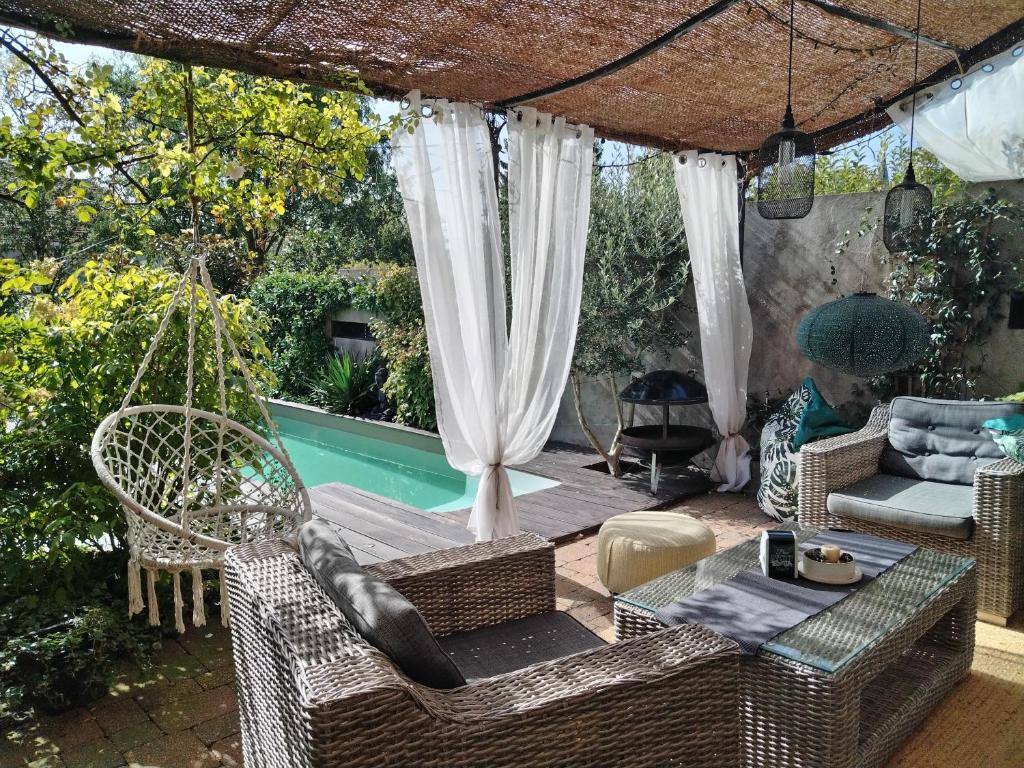 eine Terrasse mit einer Hängematte und einem Pool in der Unterkunft Chambre d'hôtes Les Magnolias in Pontpierre