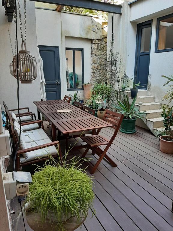 a wooden deck with a wooden table and chairs at Loft en duplex 270 m2 &amp; Jardin patio terrasse sauna in Chaville