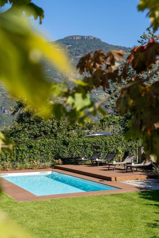 a swimming pool in a yard with two chairs at Apartments Villa Julia in Lana