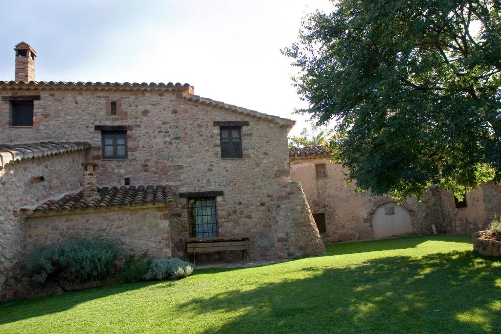 un antiguo edificio de piedra con un banco en el patio en Masia Sapera, en Pontons