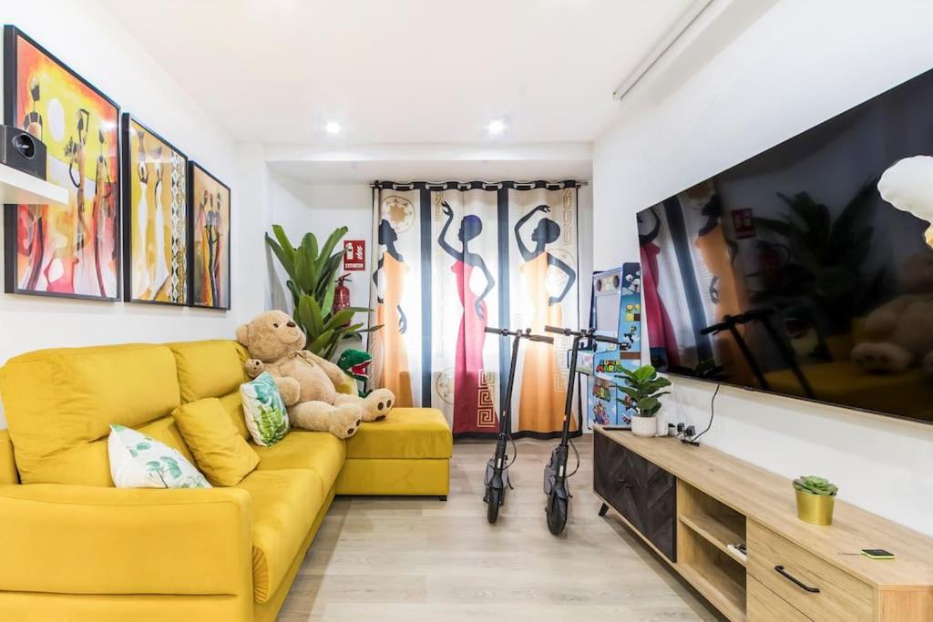 a yellow couch in a living room with a teddy bear at LUJO: Parking, Proyector, Maquinita y Patinetes in Oviedo