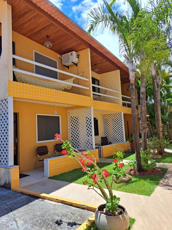 ein gelbes Haus mit einer Palme davor in der Unterkunft Vilage Taipan 02 - Praia Stella Maris in Salvador