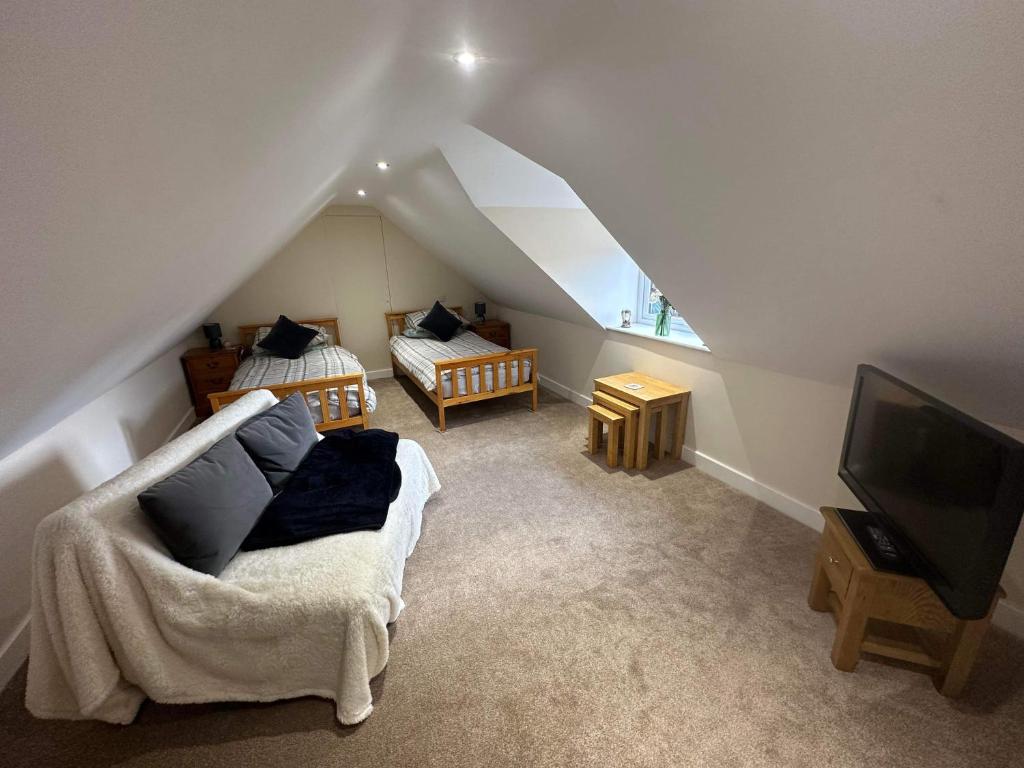 a attic room with two beds and a television at The Barn in South Witham