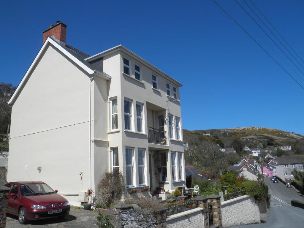 a white house with a red car parked in front of it at Fern Villa B&B in Fishguard