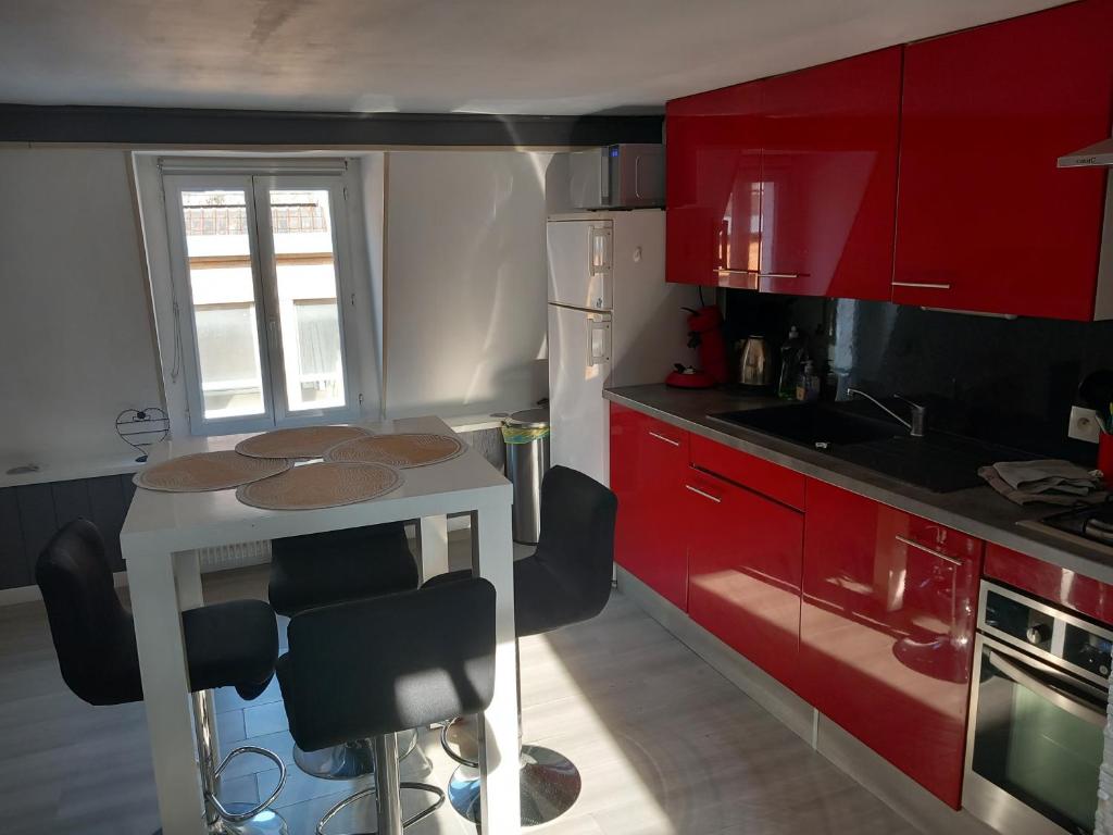 une cuisine avec des placards rouges, une table et des chaises dans l'établissement Appart'Hotel Saint-Omer, à Saint-Omer