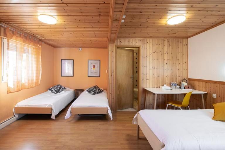 1 Schlafzimmer mit 2 Betten, einem Tisch und einem Schreibtisch in der Unterkunft Motel-Restaurant 13 Etoiles in Sierre