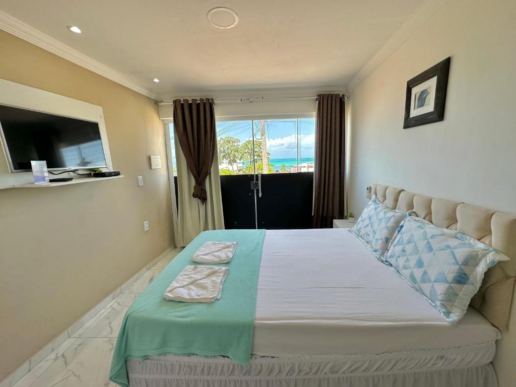 a bedroom with a large bed with a large window at Pousada Maresia in Maragogi