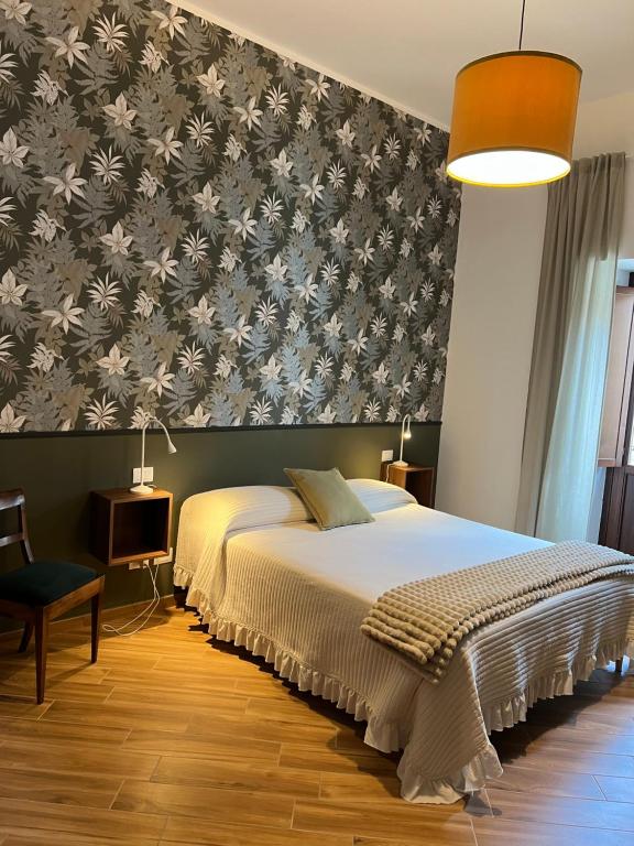 a bedroom with a bed and a wallpaper with flowers at Antica Dimora San Crisante - centro storico in LʼAquila