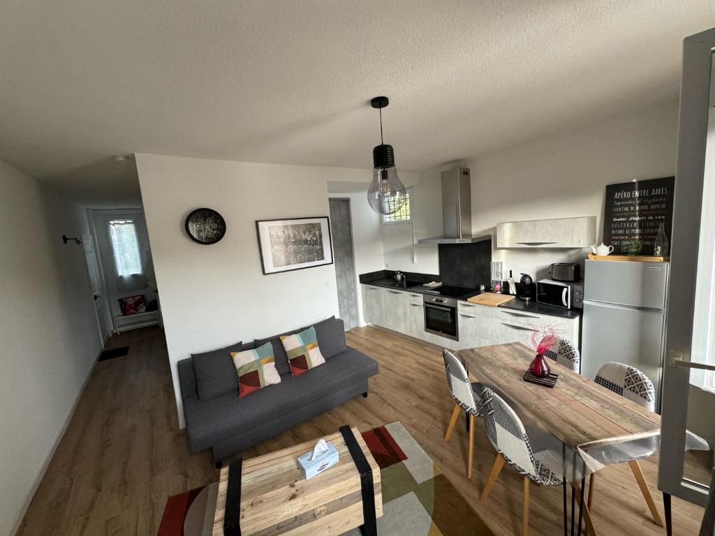 een woonkamer en een keuken met een bank en een tafel bij Appartement Le Madargue idéalement placé in Châtel-Guyon