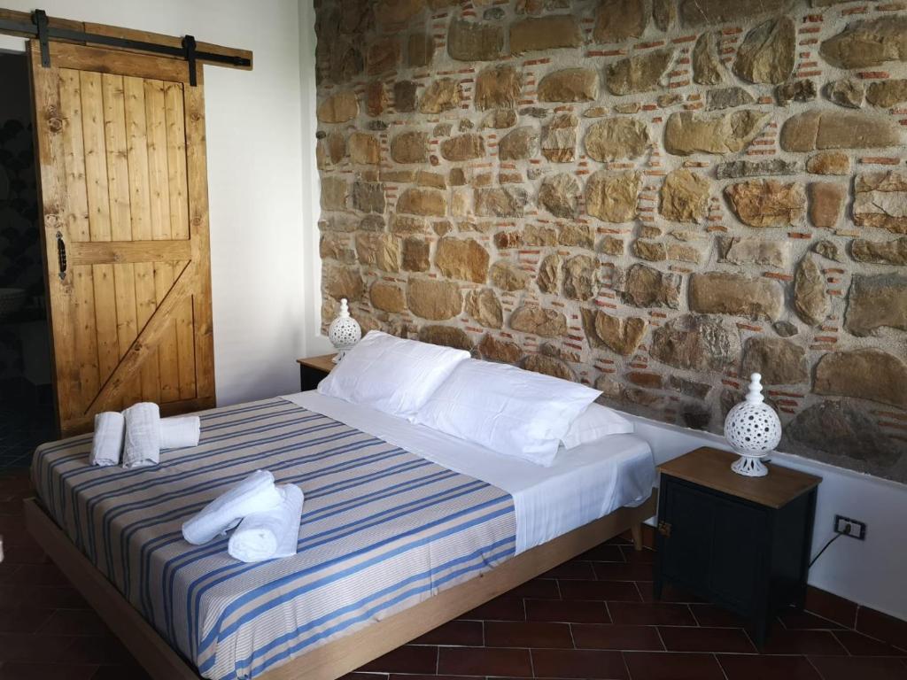 una camera con letto e parete in pietra di ficodindia Suite & Apartments a Santo Stefano di Camastra