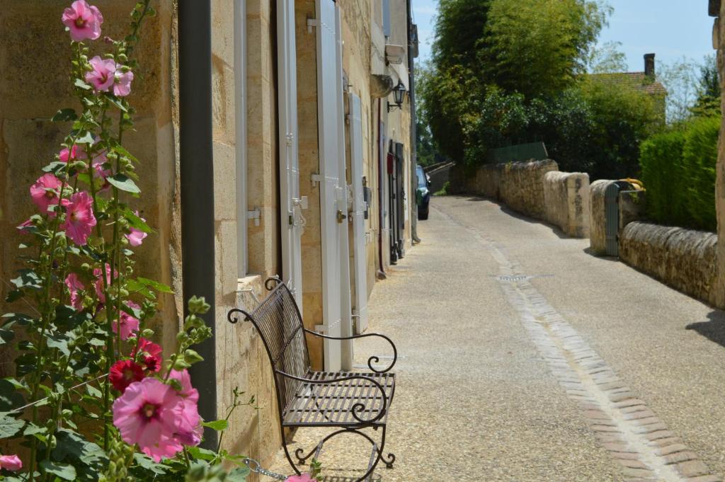 een bankje op een stoep naast een gebouw met roze bloemen bij Logis des Jurats in Saint-Émilion