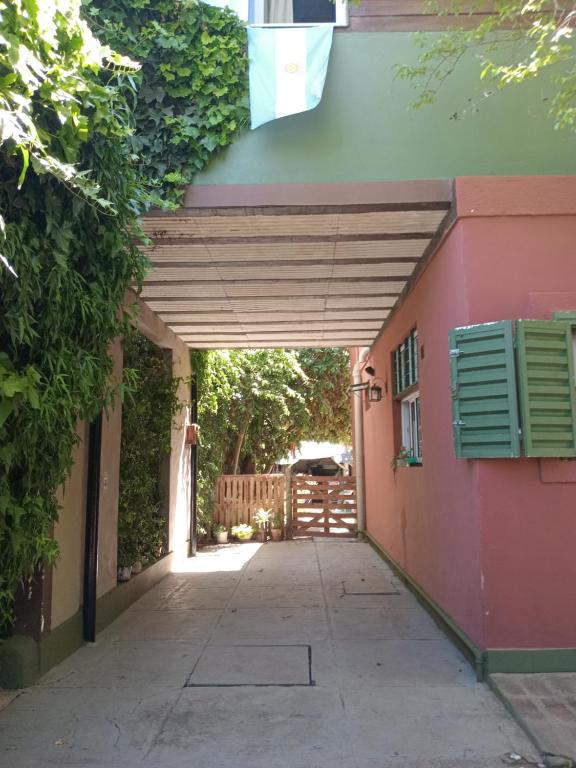 a walkway leading into a pink building with awning at El olivo apart in City Bell