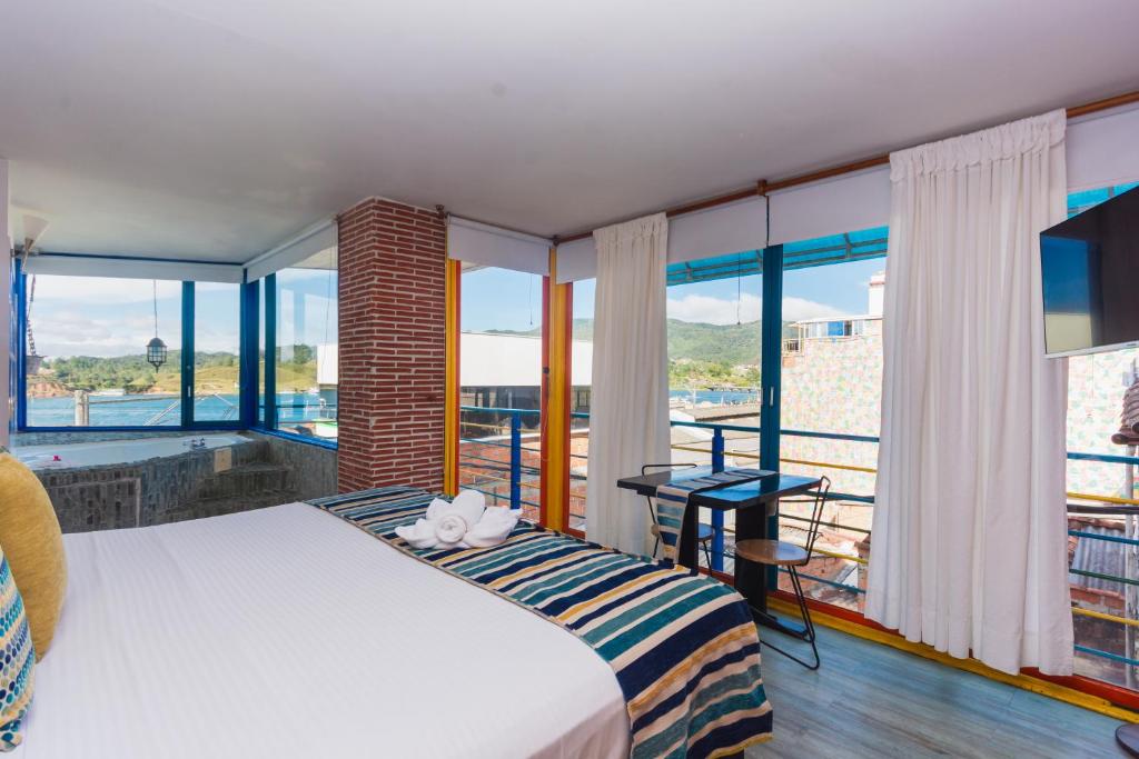 a bedroom with a bed and large windows at Hotel Guatatur in Guatapé