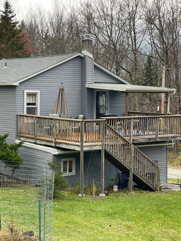 a house with a deck on the side of it at Quite Cozy Wooded Hideaway in Livingston Manor
