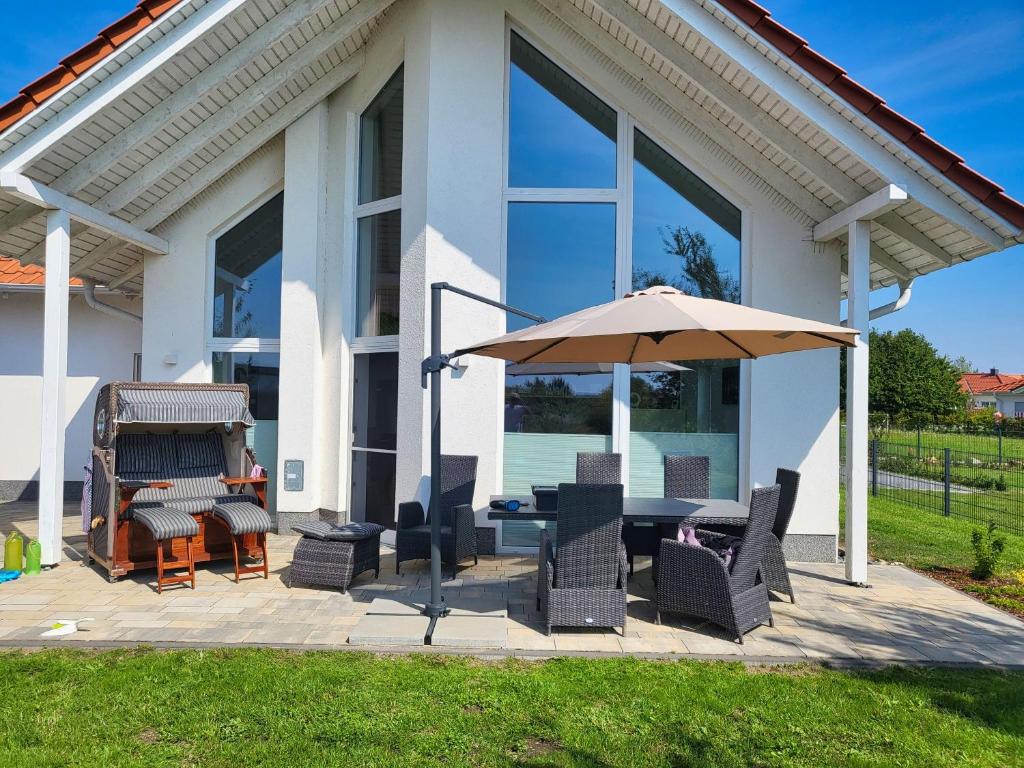 a patio with a table and an umbrella at modernes Ferienhaus mit Kamin, Garten und eigener Sauna - Ferienhaus Meerfreude in Vaschvitz