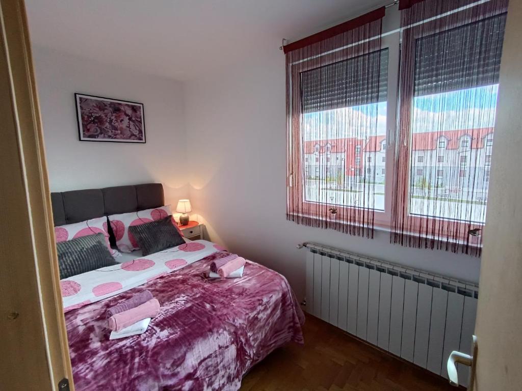 a bedroom with a bed and two windows at Apartman Ante in Gospić