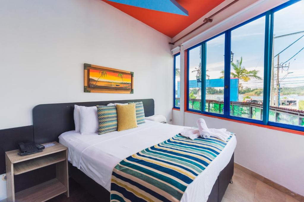 a bedroom with a bed and a large window at Hotel Guatatur in Guatapé