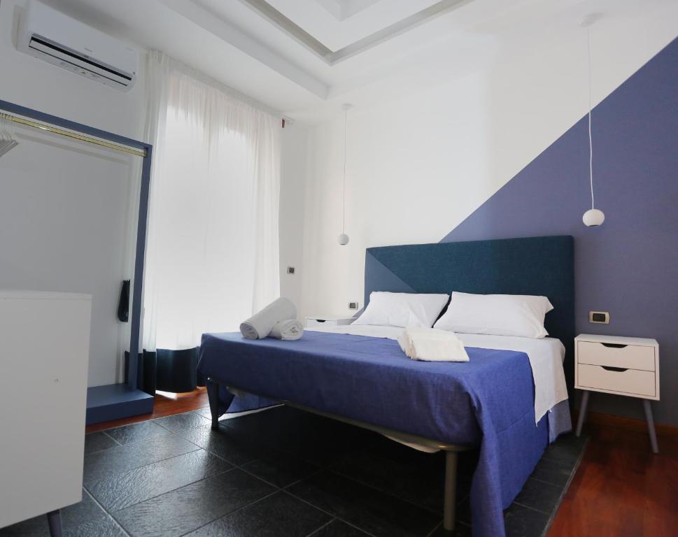 Schlafzimmer mit einem blauen und weißen Bett und einem Fenster in der Unterkunft Ersilia Chiaia Suite in Neapel
