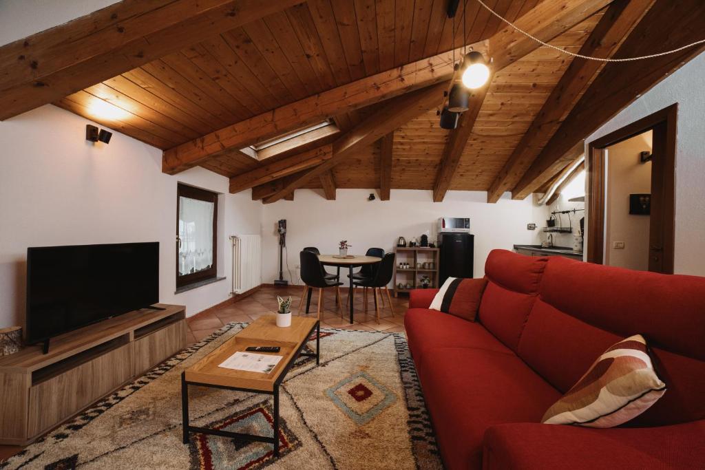 uma sala de estar com um sofá vermelho e uma televisão em Maison Petit Rouge Aosta em Aosta