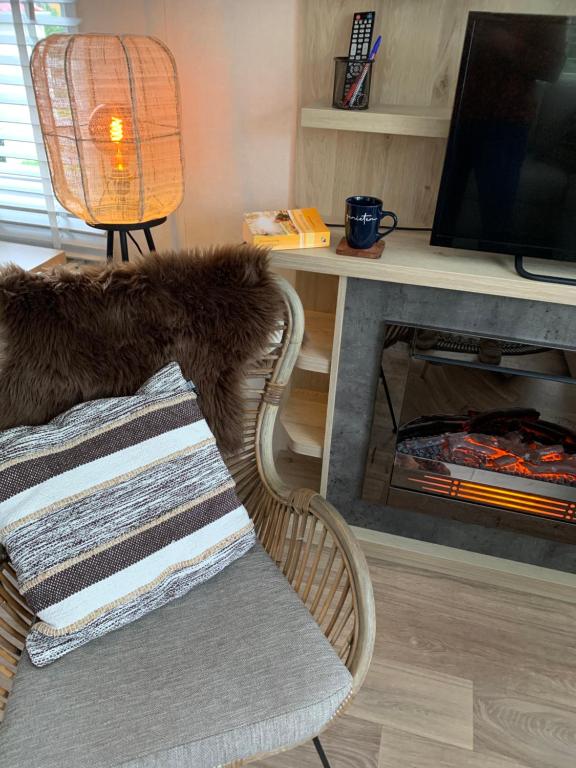 een woonkamer met een stoel en een tafel met een televisie bij Luxe 4-persoons chalet zon zee strand Renesse. in Renesse