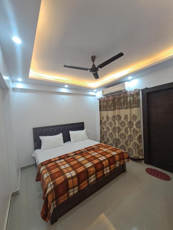 1 dormitorio con 1 cama y ventilador de techo en Gokul 3BHK Service Apartment Bharat City Ghaziabad near Hindon Airport en Ghaziabad