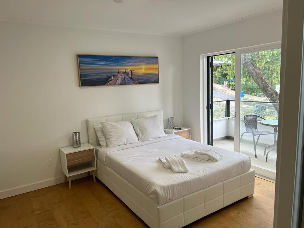ein weißes Schlafzimmer mit einem Bett und einem Fenster in der Unterkunft Large double room 2 with en-suite bathroom and Belcony in Oeiras