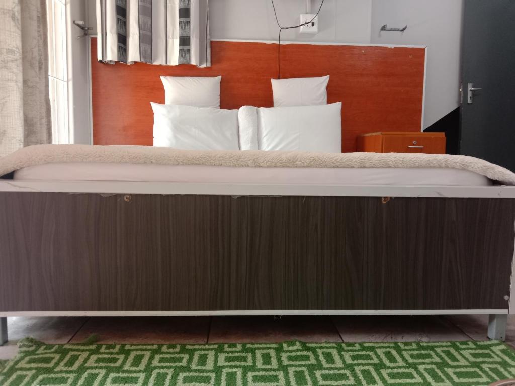 een groot bed met een houten hoofdeinde in een slaapkamer bij Silent Night Guest House Sunnyside Pretoria in Pretoria