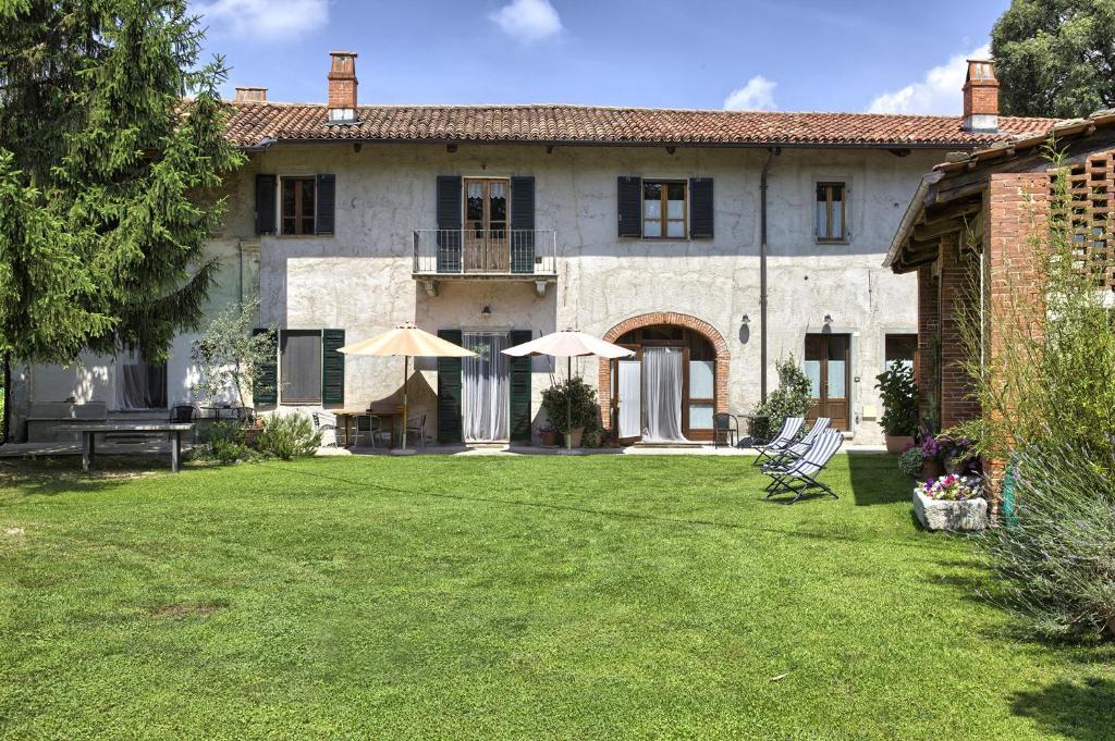 une maison avec deux chaises longues et des parasols dans la cour dans l'établissement B&B Cascina Moncrava, à Ivrea