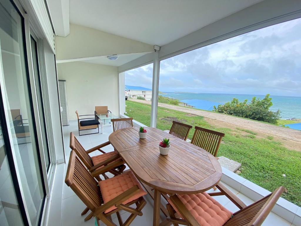 a wooden table and chairs on a balcony with the ocean at Résidence Makéra in Cul de Sac