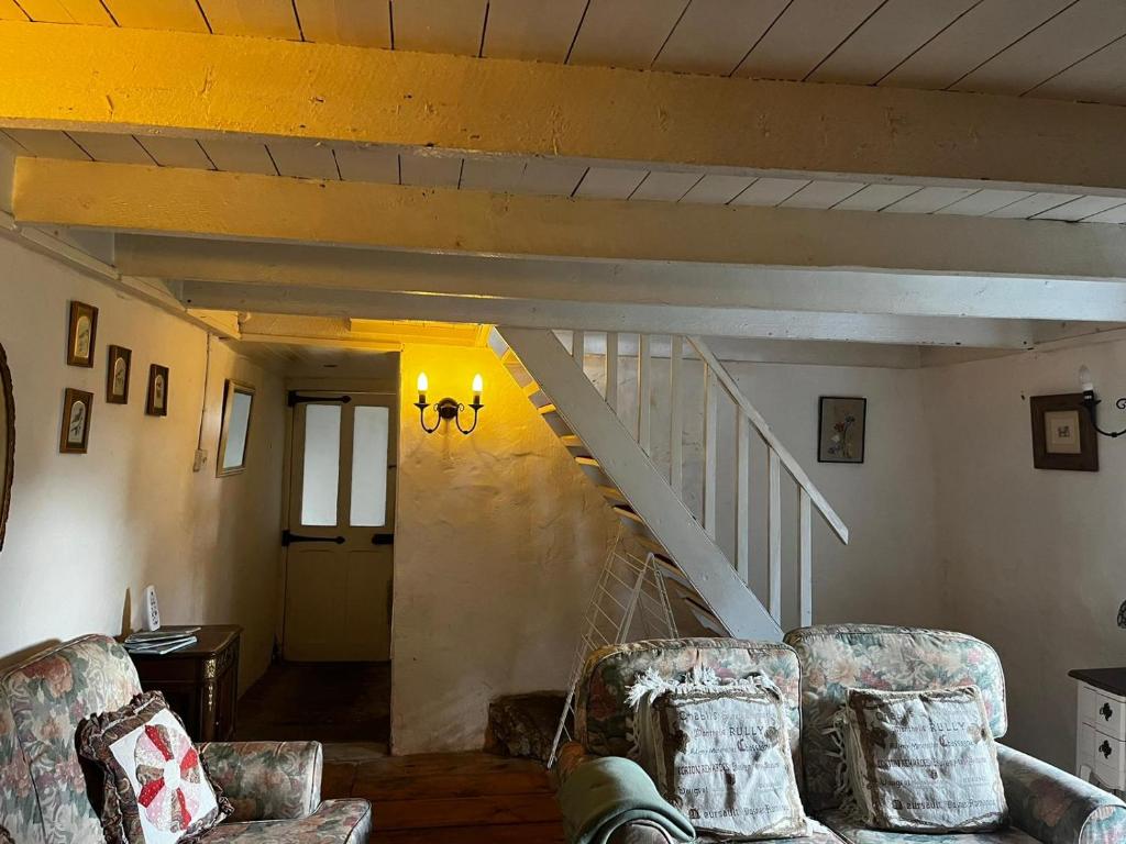 a living room with two chairs and a staircase at 3 bed cottage in Ahakista West cork in Ahakista