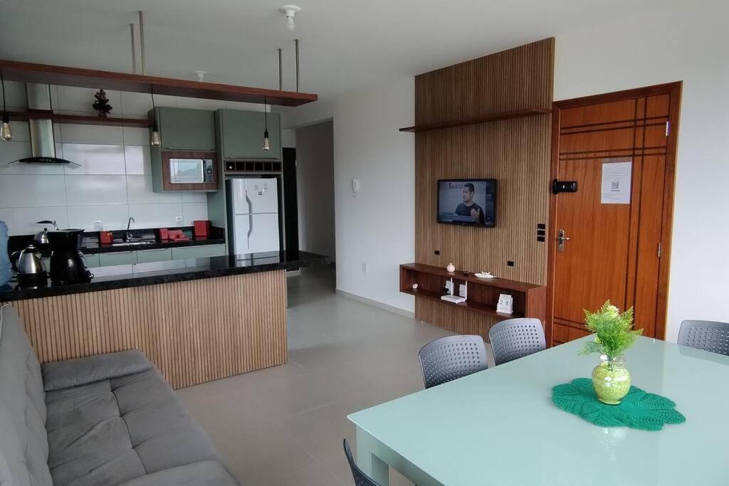 a living room with a table and a kitchen at Apartamento Praia do Sonho in Palhoça