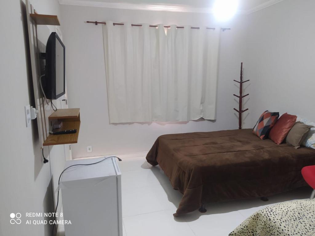 1 dormitorio con 1 cama y TV de pantalla plana en Suíte praia dos Anjos, en Arraial do Cabo