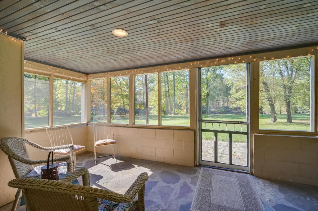 eine abgeschirmte Veranda mit Stühlen und Fenstern in der Unterkunft Charming Great Cacapon Cabin with Screened-In Porch! in Morton Grove