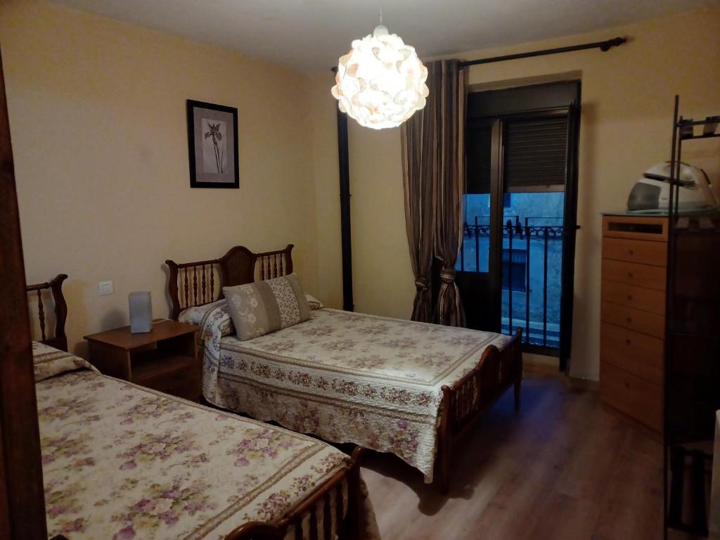 una camera con due letti e un lampadario a braccio di Casa rural san juan a San Juan del Monte
