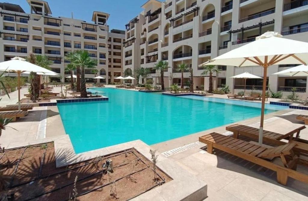 a large swimming pool with benches and umbrellas in front of a building at Cordoba suites Penthouse with private open air Jacuzzi in Hurghada