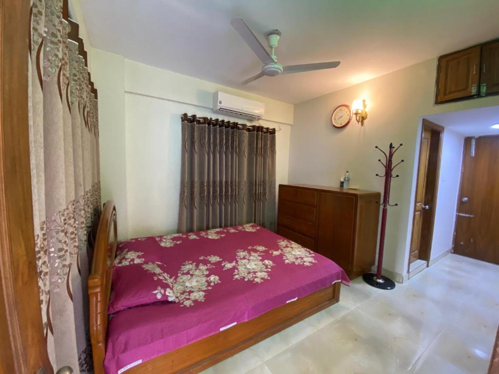 een slaapkamer met een bed met een paarse deken bij Realx in Dhaka