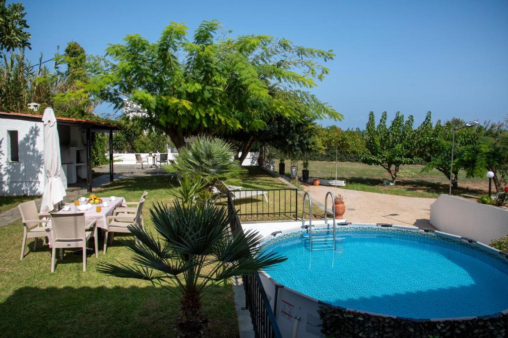 a swimming pool in a yard with a table and chairs at Villa Eleni 100m from the sea in Ropanianá