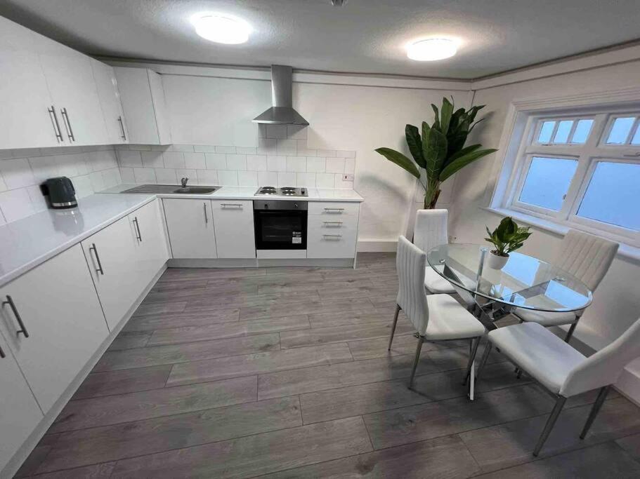 a kitchen with white cabinets and a table and chairs at The Swan Apartment Ruislip in Ruislip