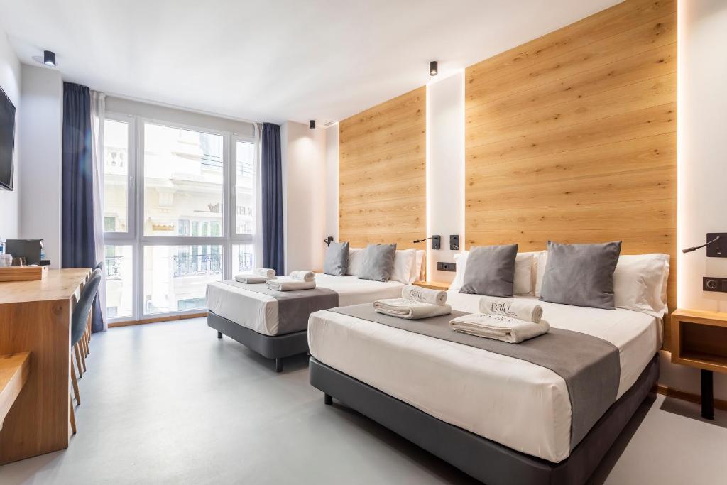 Una habitación de hotel con dos camas y una gran ventana. en NALU Valencia Boutique Rooms, en Valencia