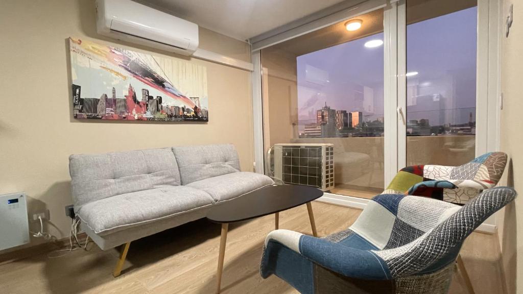 a living room with a couch and chairs and a window at Depto central, parking, moderno in Chillán