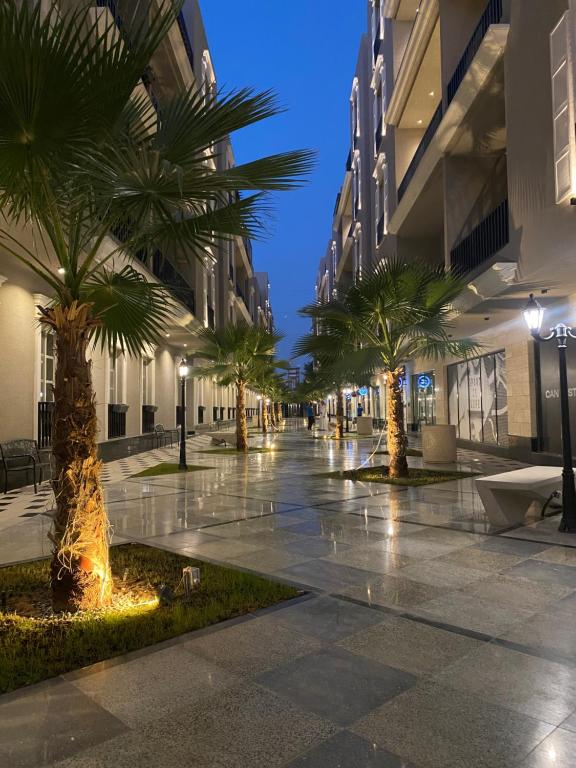 a street with palm trees and buildings at night at Elegant 3BD Condo near Boulevard in Riyadh