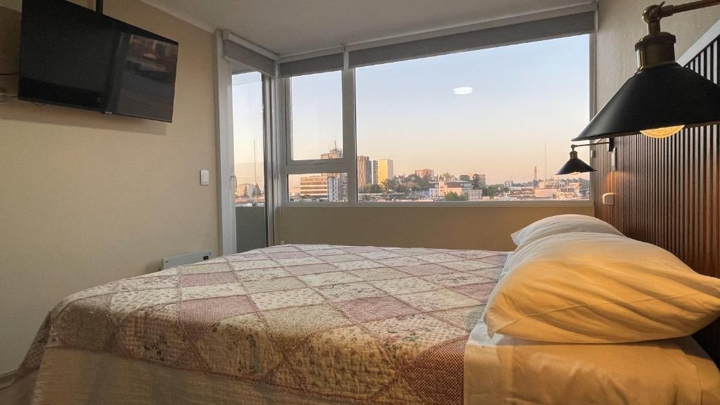 a bedroom with a bed and a large window at Depto central, parking, moderno in Chillán