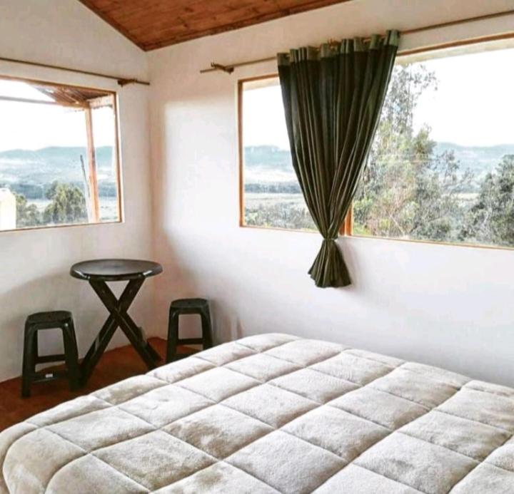 a bedroom with a bed and a table and a window at El Mirador de Juan in Guasca