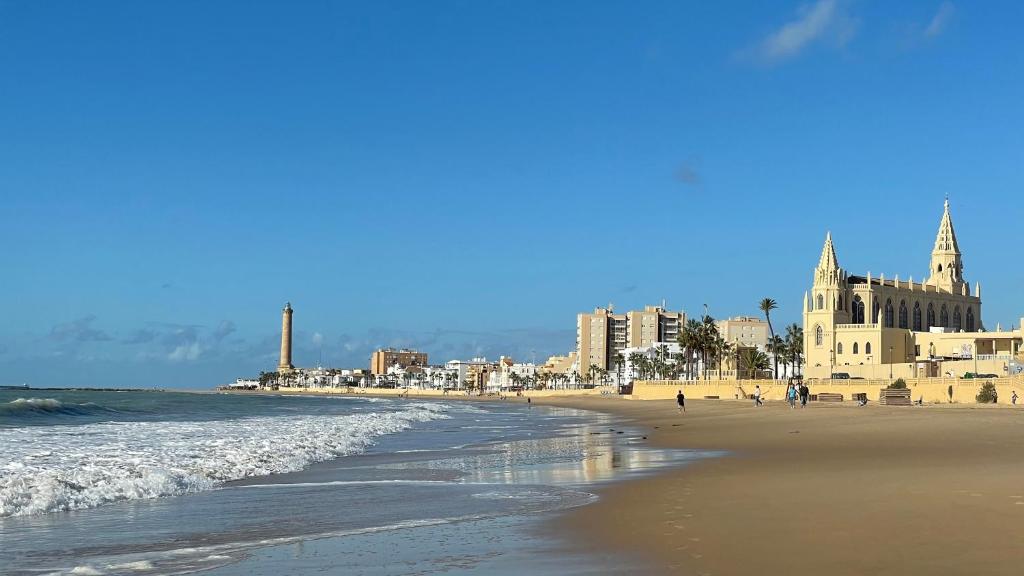 una playa con gente caminando por la arena y el océano en Casa Santuario de Regla, en Chipiona