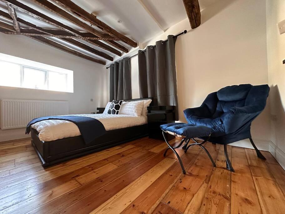 een slaapkamer met een bed, een stoel en een raam bij The Signature 1360’s - Modern Apartment in Barnet