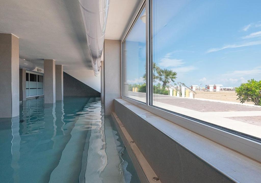 a swimming pool in the side of a building with a window at Unico Hotel Caorle in Caorle