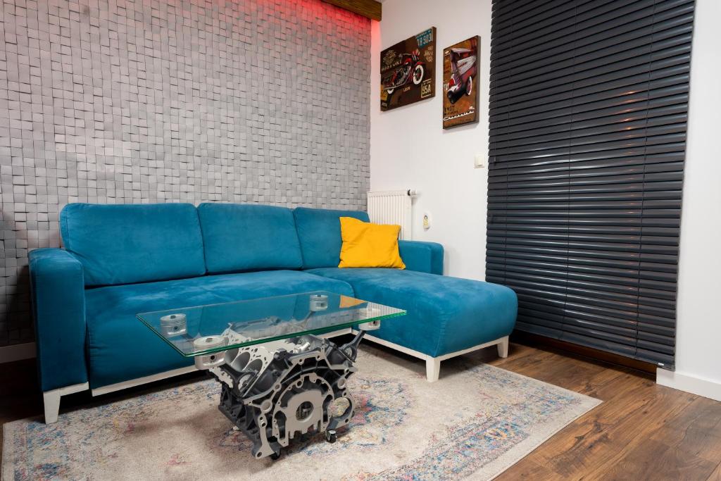 um sofá azul numa sala de estar com uma mesa de vidro em Kasprzaka 31A by Perfect Apart em Varsóvia