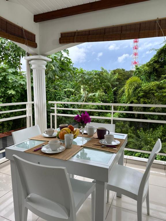 a white table and chairs on a porch with a view at Appartement Coeur de Papillon in Baie-Mahault