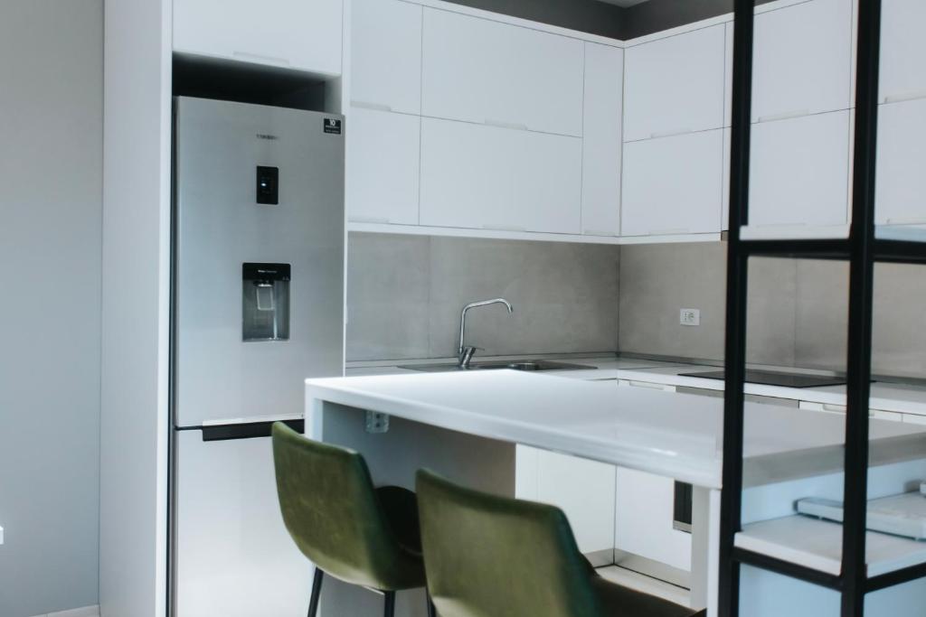 a kitchen with white cabinets and a sink and chairs at The Heart of Tirana in Tirana